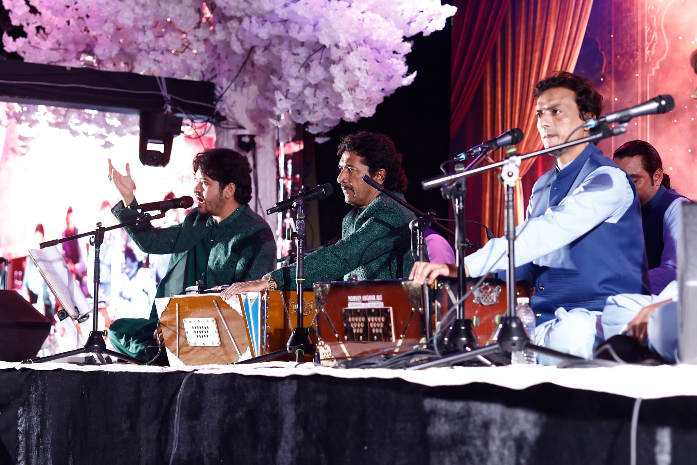 Qawwali ensemble performing on stage with harmoniums